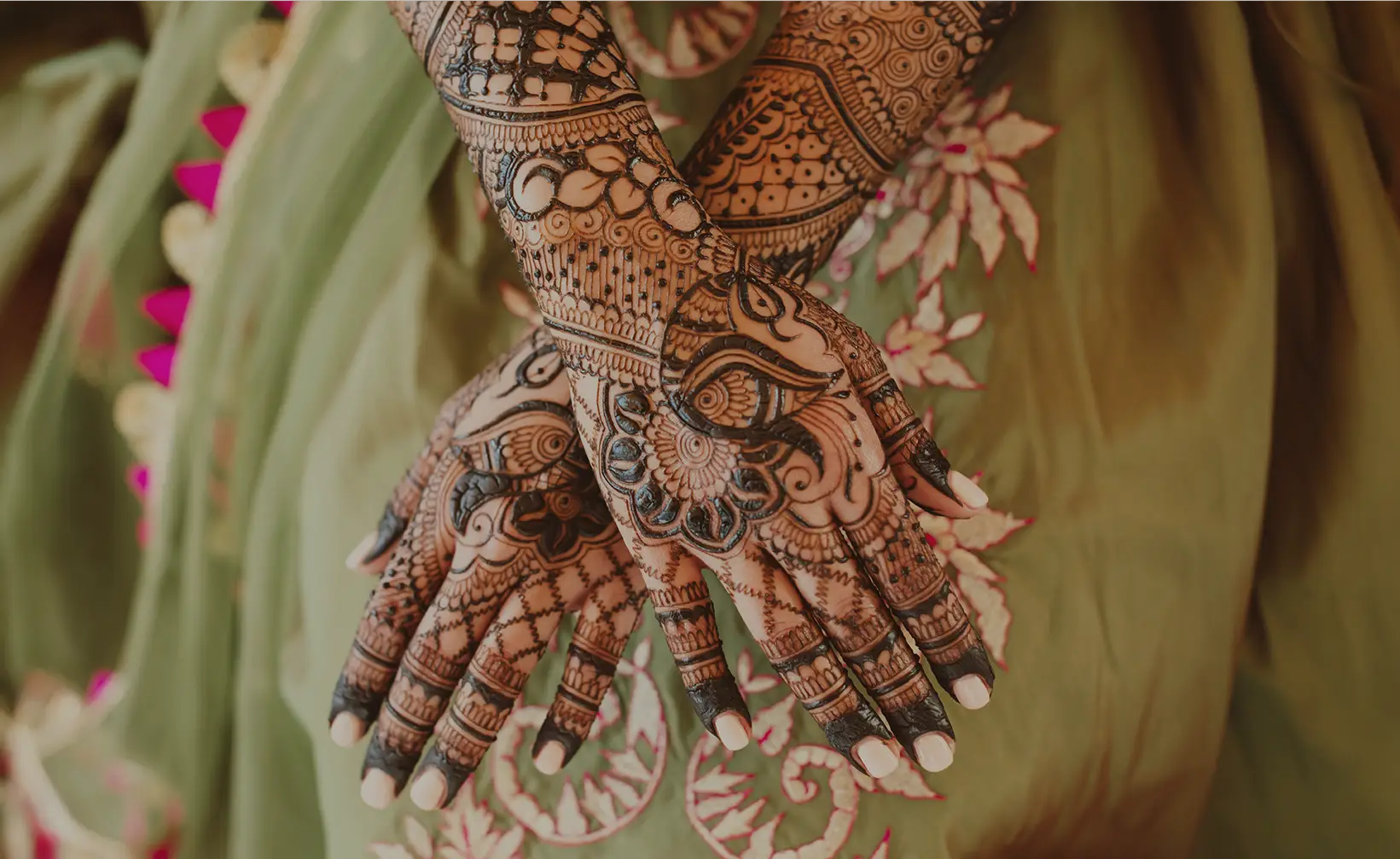 Henna-decorated hands on green fabric